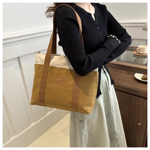 Detailed view of bicolor canvas tote with leather Fashion tag and brown woven straps