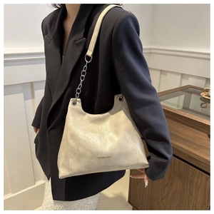 Dettaglio borsa a spalla beige in ecopelle con catena metallica indossata dalla modella