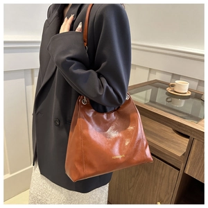 Dettaglio della borsa tote in pelle marrone con scritte dorate e occhielli in metallo