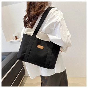 Detailed view of canvas tote bag with contrast trim and brown fashion leather patch