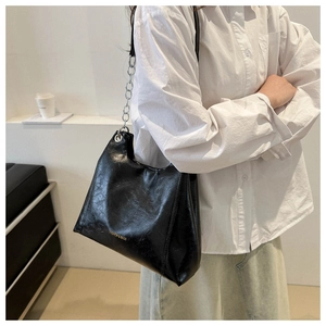 Dettaglio borsa a spalla in pelle cerata nera con catena d'argento e logo goffrato
