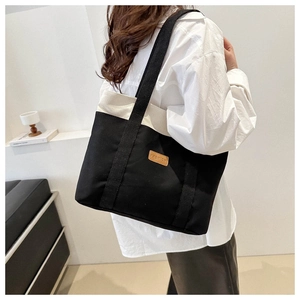 Detail view of fashion canvas tote bag with contrast black and white patchwork and leather label