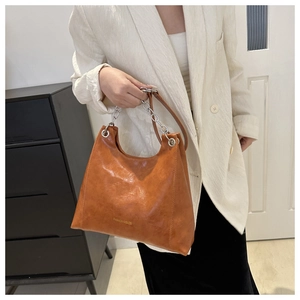 Dettaglio della borsa a tracolla in pelle lucida marrone con catena argento e logo moda