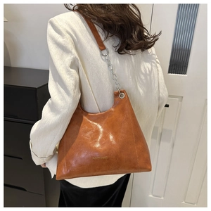 Dettaglio borsa a spalla retrò marrone con logo dorato e tracolla a catena
