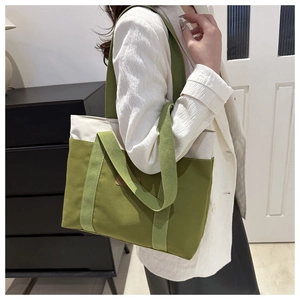Close-up of canvas tote bag with avocado green handles and beige fabric texture