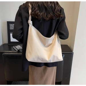 Minimalist cream tote bag with knotted strap detail and pebbled leather texture on model