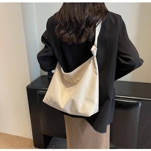 Detail of minimalist cream leather tote bag with stylish knotted strap shown on model back