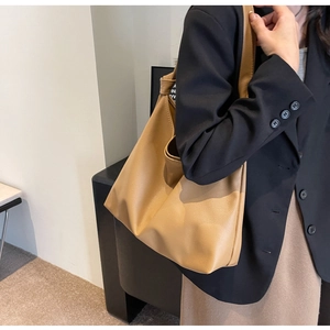Detail view of large camel tote bag in pebbled faux leather worn with casual outfit
