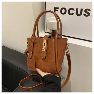 Detail of a brown vintage bucket bag with metal buckle lock and fashion leather tag