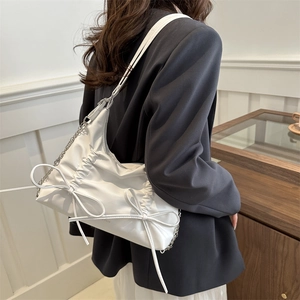 White faux leather shoulder bag with double bows and silver chain strap on a model