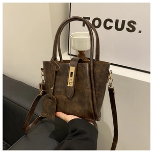 Close-up of a vintage brown leather bucket bag with a golden metal lock and strap