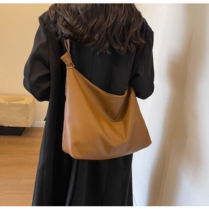 Detail of caramel pebbled leather tote bag with unique knot shoulder strap decoration