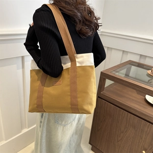 Minimalist canvas tote bag with contrast stitching and brown strap for daily commute