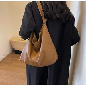Detail view of caramel brown leather tote with knotted strap and pebble texture