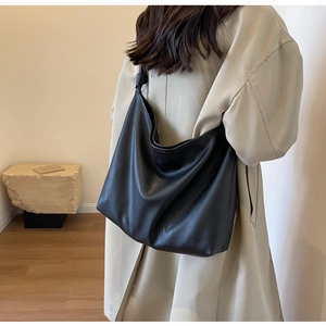 Close-up of black pebbled leather hobo bag on shoulder showing texture and slouchy drape