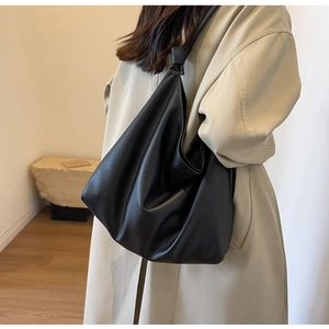Detail of black pebbled leather hobo bag showing a unique knotted strap design for women