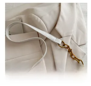 Detail of white leather shoulder strap and thick gold metal chain on a crossbody bag