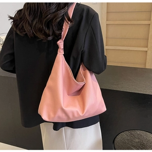 Detail of pink large tote bag showing textured leather and knotted strap on model shoulder