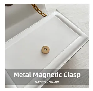 Detailed close-up of a white leather bag featuring a gold round magnetic snap closure