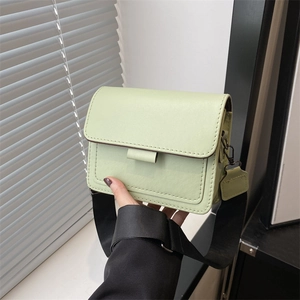Chic light green PU leather square crossbody bag with wide black strap held by hand