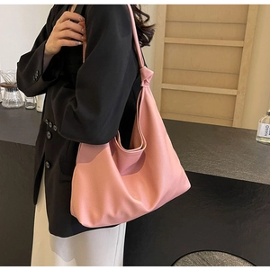 Detail of a dusty pink Hobo tote bag featuring a large decorative knot on the shoulder strap