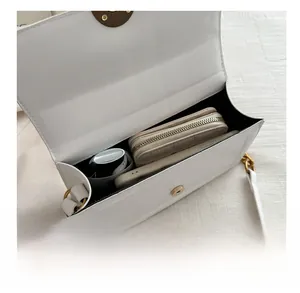 Detail view of white minimalist flap bag interior showing capacity for wallet and phone