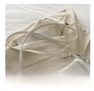 Detail view of white PU leather bag with silver metal chain and fashion brand logo