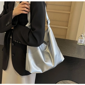 Detailed view of the knotted shoulder strap on a silver metallic tote bag