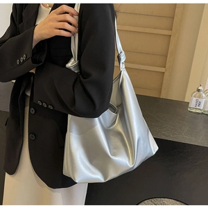 Detail of silver metallic tote bag featuring a decorative shoulder strap knot on model