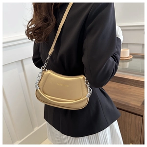 Close-up of golden crescent bag with pleated silk texture and silver chain handle detail