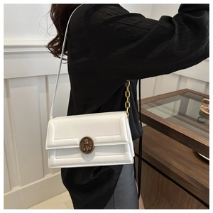 Close-up of a white rectangular bag featuring a vintage gold embossed circular buckle clasp