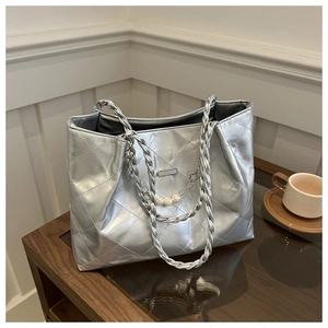 Detail of silver quilted tote bag featuring pearl chain charms and woven handles