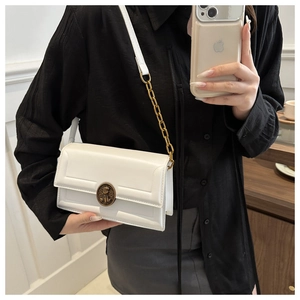 Detail of white leather crossbody bag with golden chain strap and lion head buckle