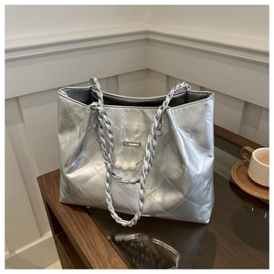 Detail of silver quilted tote bag featuring pearl accents and woven chain shoulder strap