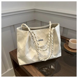 Detail of cream quilted tote bag with woven handles and elegant pearl floral charms