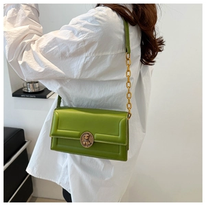 Detailed shot of emerald green crossbody bag with vintage gold bear embossed lock and chain