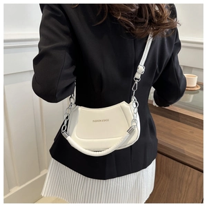White crescent PU leather shoulder bag with silver chain worn by model in a suit