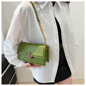 Detail of a grass green leather crossbody square bag with a golden bear embossed buckle