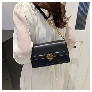 Detail view of black rectangular crossbody bag with vintage gold buckle and chain strap