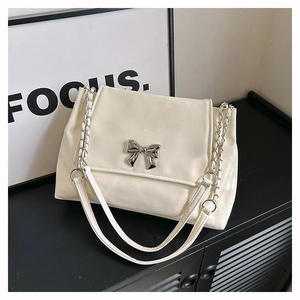 Close-up of minimalist cream white bag with silver butterfly buckle and chain strap