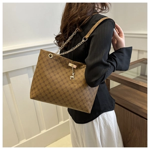 Detailed side view of brown printed tote bag with golden deer charm and chain strap