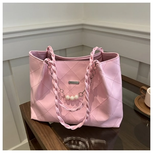 Close-up of pink quilted tote bag featuring pearl chain details and woven handles