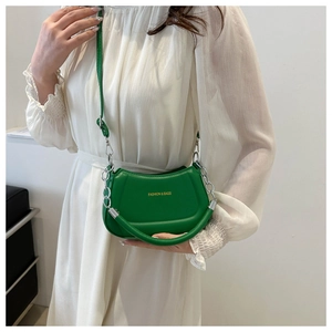 Detail of green crescent crossbody bag with silver chain strap and brand logo