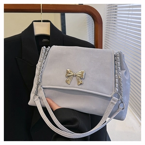 Detail of light blue flap bag featuring a silver metal butterfly and chain strap
