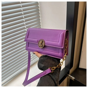 Detail of purple square bag with vintage gold lion badge and matte leather texture