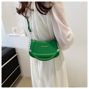 Detail of green half-moon crossbody bag with silver chain strap on white dress