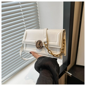 Detail view of white crossbody bag with quilted texture and bronze bear metal emblem