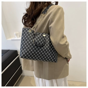 Detail of vintage large black tote bag with white geometric print and chain strap on model
