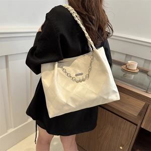 Quilted beige tote bag with woven shoulder strap and pearl chain charm accessory