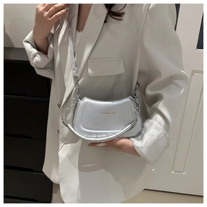 Silver crescent shoulder bag with metallic finish and metal chain detail on model